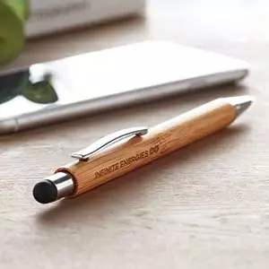 Penna in legno con logo e rifiniture metallo su scrivania in legno con smartphone sullo sfondo
