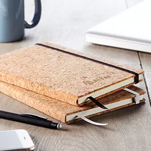 articoli di cancelleria: quaderni in sughero, penne, smartphone e tazza su tavolo in legno
