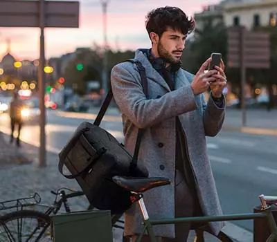 borsone palestra personalizzato uomo in bicicletta che guarda smartphone in strana al tramonto