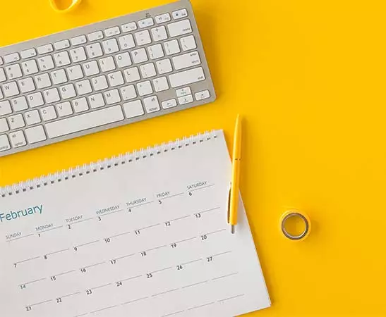calendario personalizzato da tavolo su sfondo giallo con tastiera e accessori scrivania