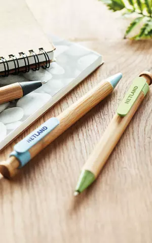 cancelleria personalizzata su base in legno con penne ecologiche e quaderno in secondo piano cancelleria personalizzata su base in legno con penne ecologiche e quaderno in secondo piano