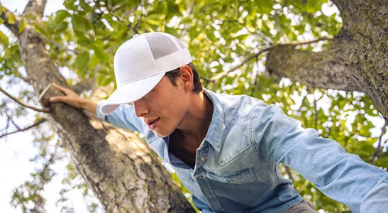 cappelli trucker personalizzabili indossati da ragazzo su un albero 