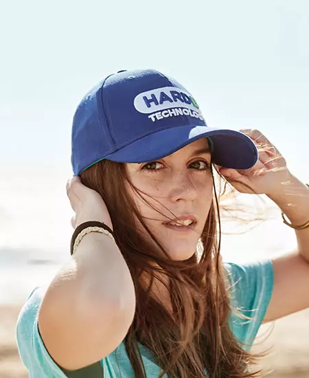 cappellini personalizzate ragazza su spiaggia con cappellino da baseball blu e logo frontale