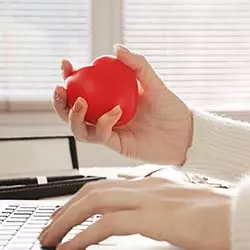 primo piano su mano di una ragazza che stringe un gadget antistress a forma di cuore rosso