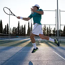 uomo che indossa completi tennis joma mentre colpisce una pallina con la racchetta