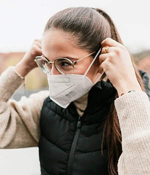 mascherina n95 indossata da ragazza all'aperto con indosso occhiali e giubbotto verse