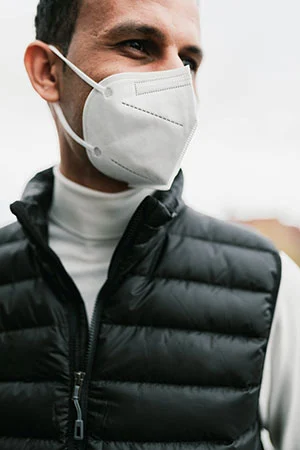 mascherine usa e getta ffp2 n95 bianca indossata da uomo all'aperto con giubbotto smanicato