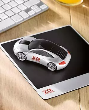 mousepad personalizzato posizionato su scrivania in legno con mouse wireless a forma di macchina