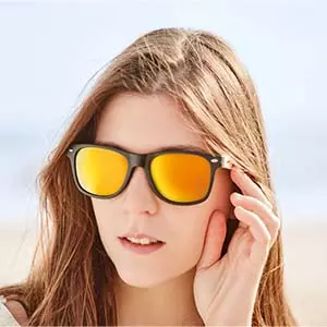 occhiali da sole economici specchiati lente riflettente giallo oro arancione indossati da ragazza con capelli lunghi castani