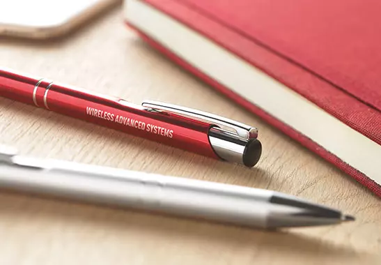 due penne in metallo personalizzate di colore rosso e grigio posate su scrivania in legno