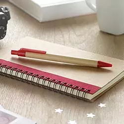 penne in cartone personalizzate su quaderno A5 a spirale appoggiato su scrivaniain legno