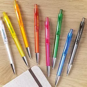 penne personalizzate online in plastica colorate su tavolo in legno con quaderno in stoffa