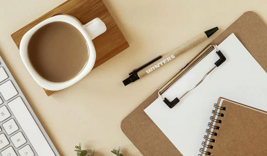 penne personalizzate e block notes con tazza di caffè su tavolo di legno