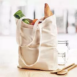 Shopper canvas posizionata su tavolo in legno con alimenti al suo interno