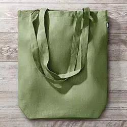 shopper ecologiche verde in canapa appoggiate su tavolo in legno naturale