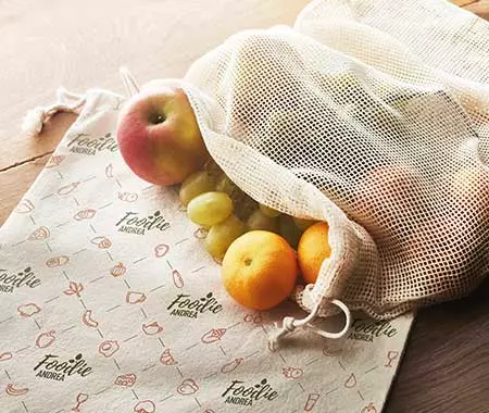 stampa borse personalizzate porta vivande con rete traspirante pe rmantenere gli alimenti freschi e asciutti in tela color corda naturale su tavolo in legno