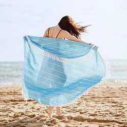 ragazza sulla spiaggia con telo mare azzurro