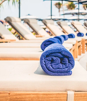 donna di spalle sulla spiaggia con telo mare  tra le mani